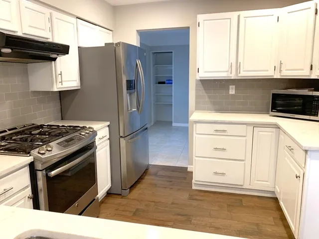 a kitchen with stainless steel appliances granite countertop a stove a refrigerator and a cabinets