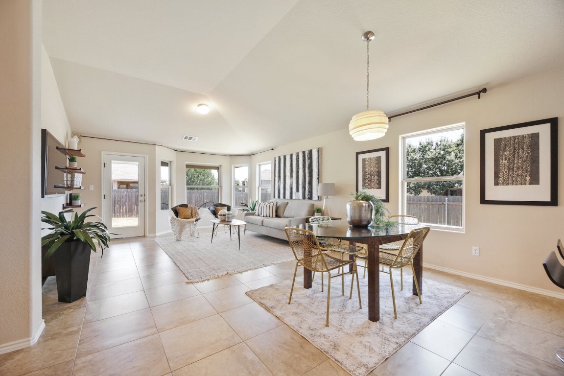a view of a dining room and livingroom furniture a rug a potted plant and a chandelier