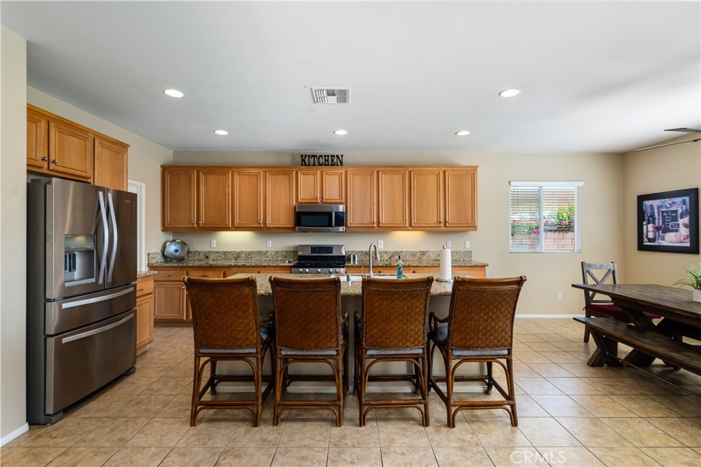 49267 Biery Street Indio, CA 92201 - Photo 6 of 28 a kitchen with stainless steel appliances granite countertop a dining table chairs refrigerator and sink