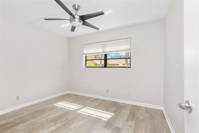 an empty room with a window and a ceiling fan