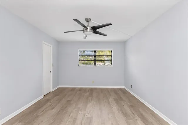 an empty room with a window and a ceiling fan
