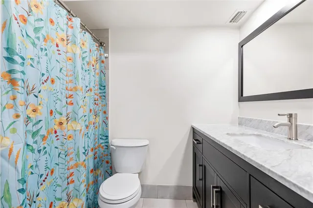 a bathroom with a granite countertop sink and a toilet