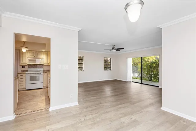 an empty room with wooden floor cabinet and windows