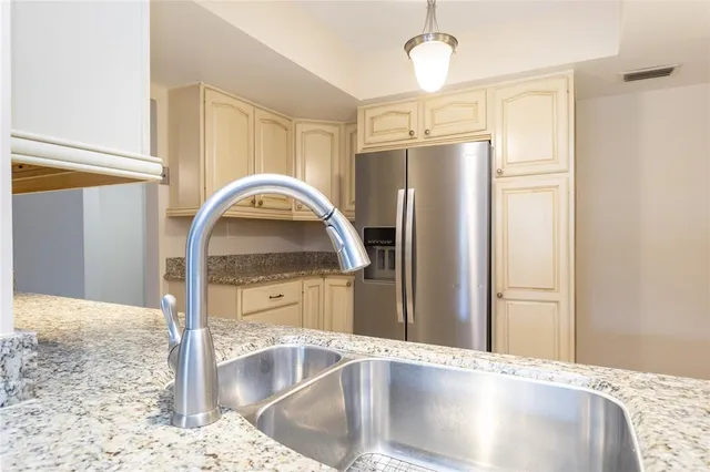 a kitchen with stainless steel appliances granite countertop a refrigerator a stove and a sink with granite countertops