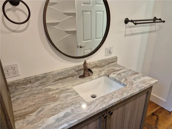 a bathroom with a granite countertop sink a mirror and a shower