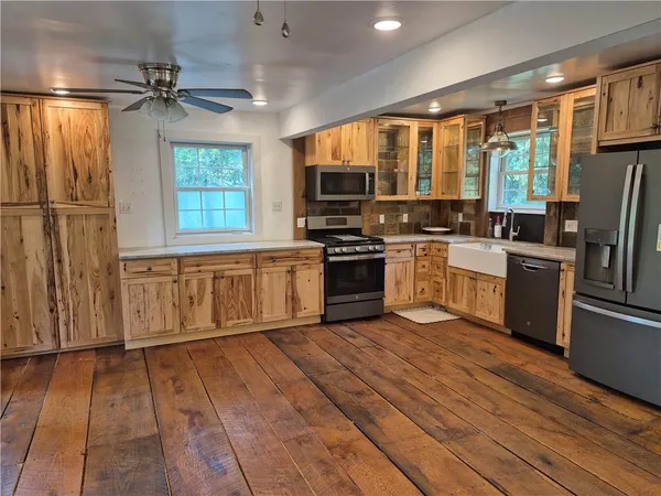 a large kitchen with stainless steel appliances granite countertop a stove top oven a sink and a refrigerator