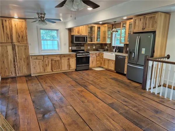 a kitchen with stainless steel appliances granite countertop a refrigerator a sink a stove and white cabinets with wooden floor