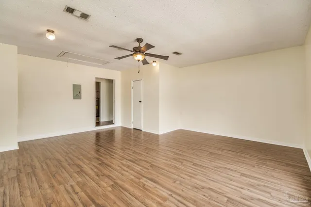 a view of empty room with wooden floor and fan