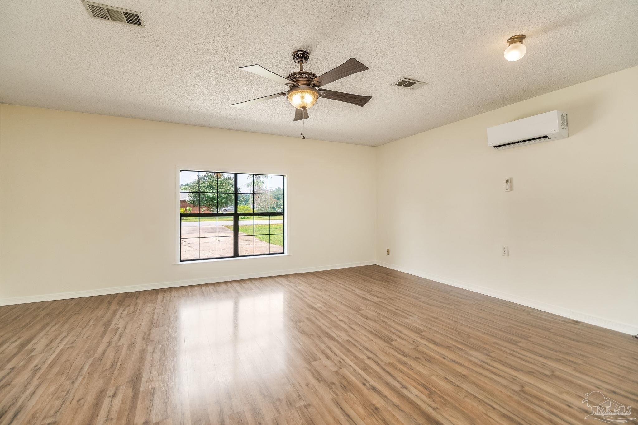 7489 Sandstone Street Navarre, FL 32566 - Photo 18 of 49 an empty room with wooden floor fan and windows