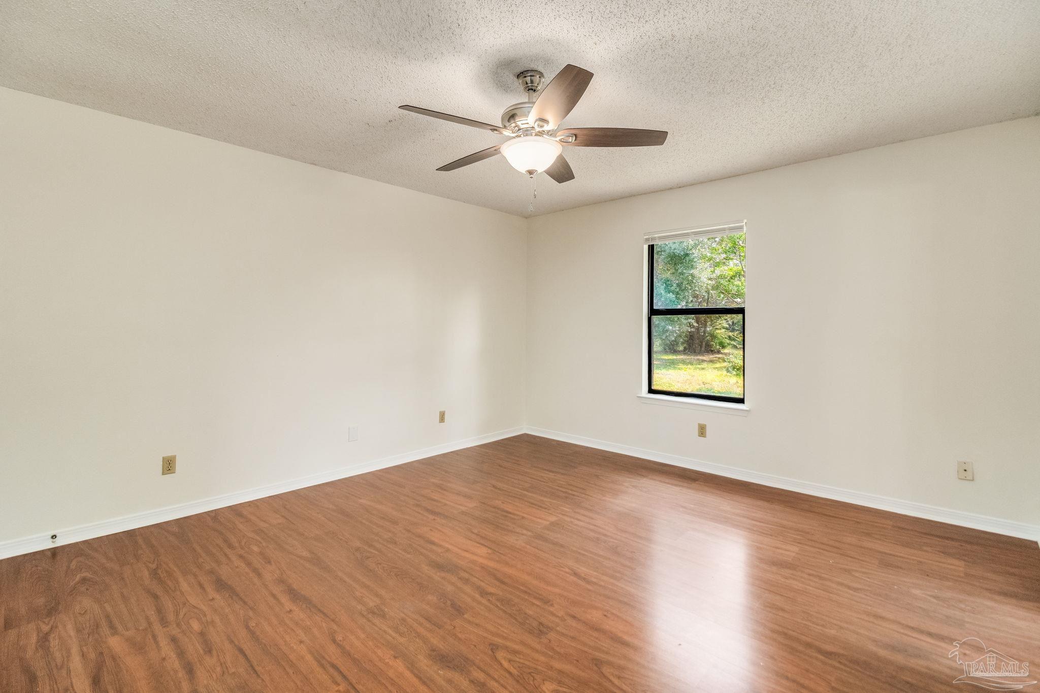 7489 Sandstone Street Navarre, FL 32566 - Photo 21 of 49 an empty room with wooden floor and windows