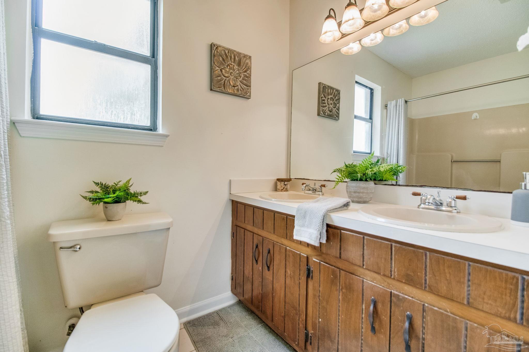 7489 Sandstone Street Navarre, FL 32566 - Photo 22 of 49 a bathroom with a granite countertop toilet sink and mirror