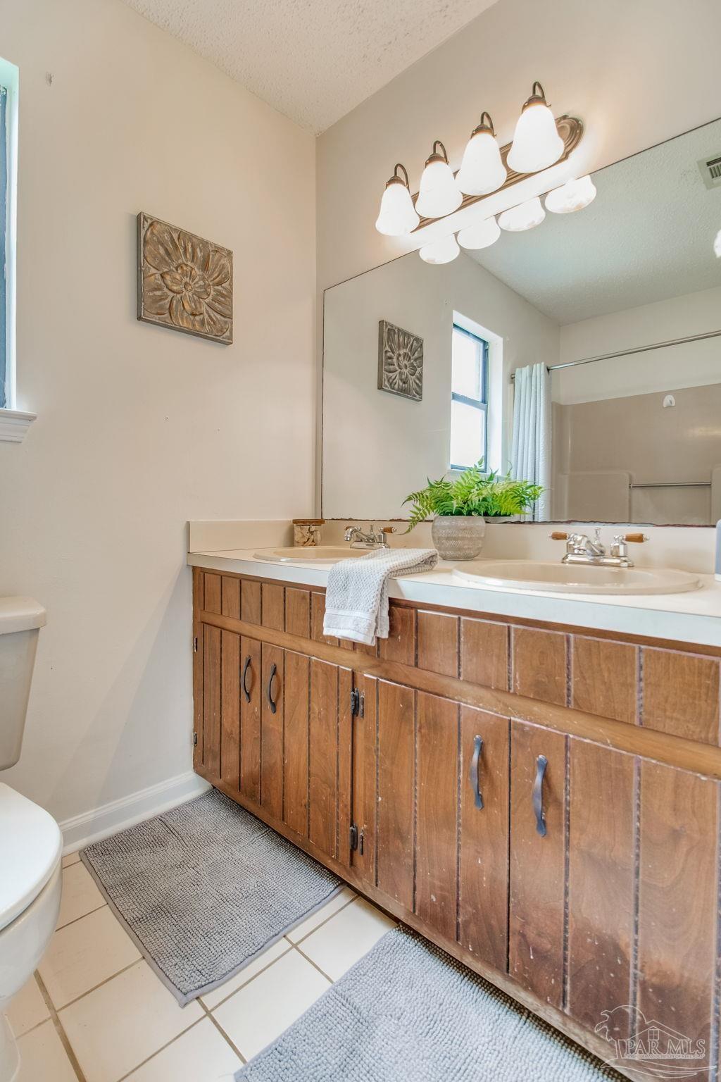7489 Sandstone Street Navarre, FL 32566 - Photo 23 of 49 a bathroom with a sink a mirror and a toilet