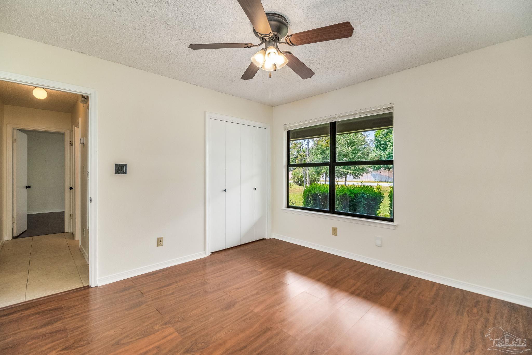 7489 Sandstone Street Navarre, FL 32566 - Photo 25 of 49 a view of an empty room with wooden floor and a window