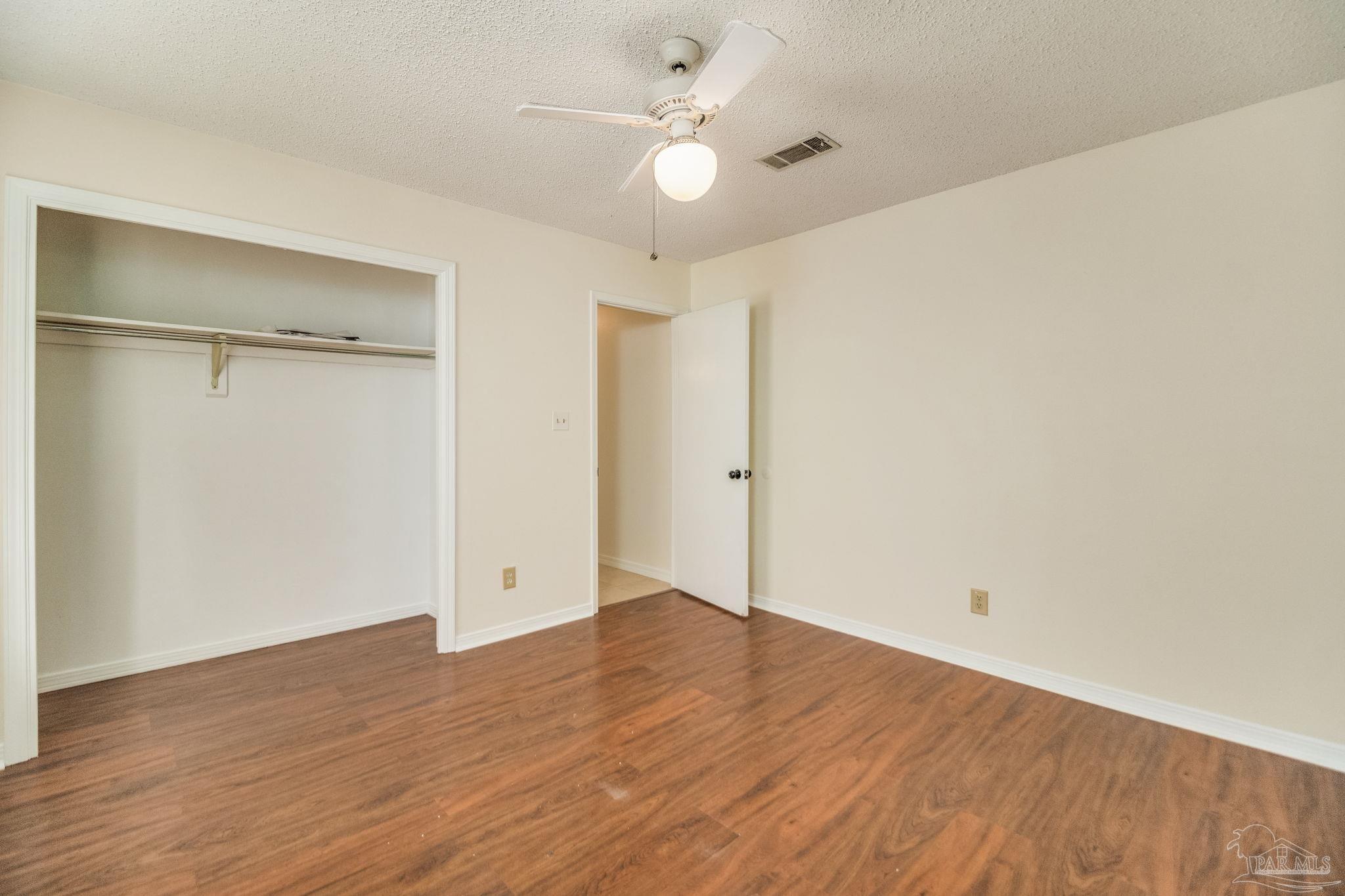 7489 Sandstone Street Navarre, FL 32566 - Photo 28 of 49 an empty room with wooden floor and a ceiling fan