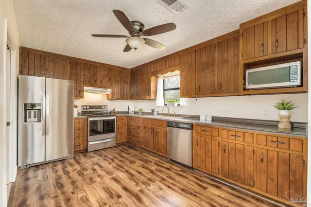 a kitchen with granite countertop a refrigerator sink and microwave