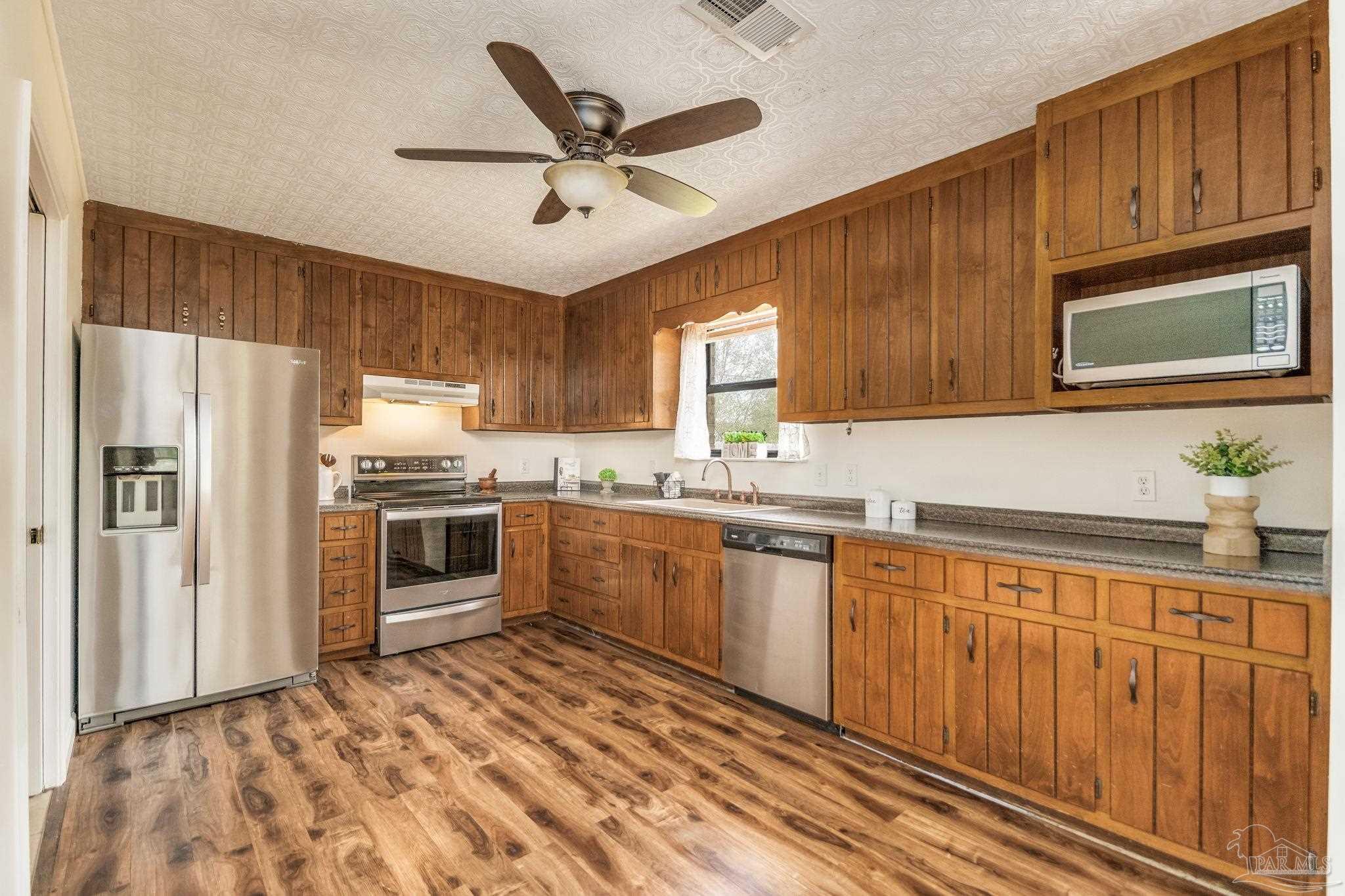 7489 Sandstone Street Navarre, FL 32566 - Photo 3 of 49 a kitchen with granite countertop a refrigerator sink and microwave