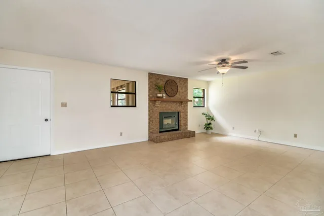 an empty room with windows and fireplace