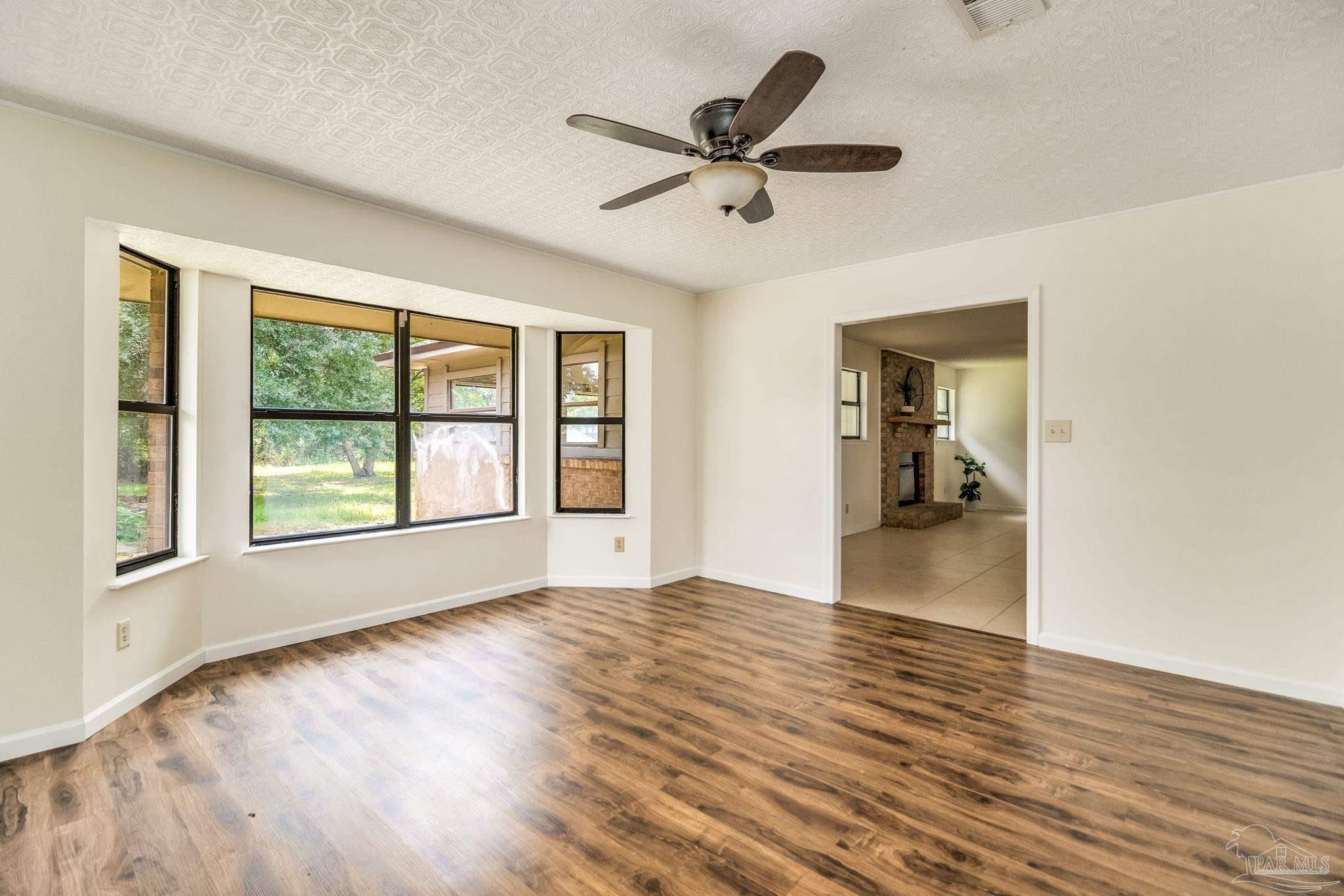 7489 Sandstone Street Navarre, FL 32566 - Photo 8 of 49 a view of empty room with wooden floor and fan