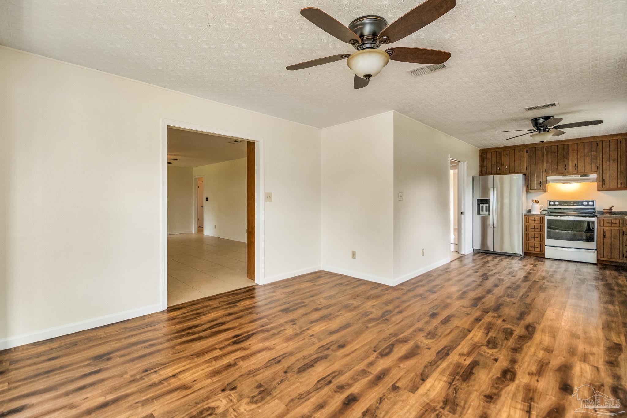 7489 Sandstone Street Navarre, FL 32566 - Photo 10 of 49 a view of empty room with wooden floor and a ceiling fan