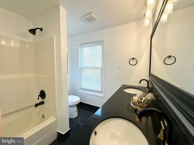 a bathroom with a granite countertop toilet sink and mirror