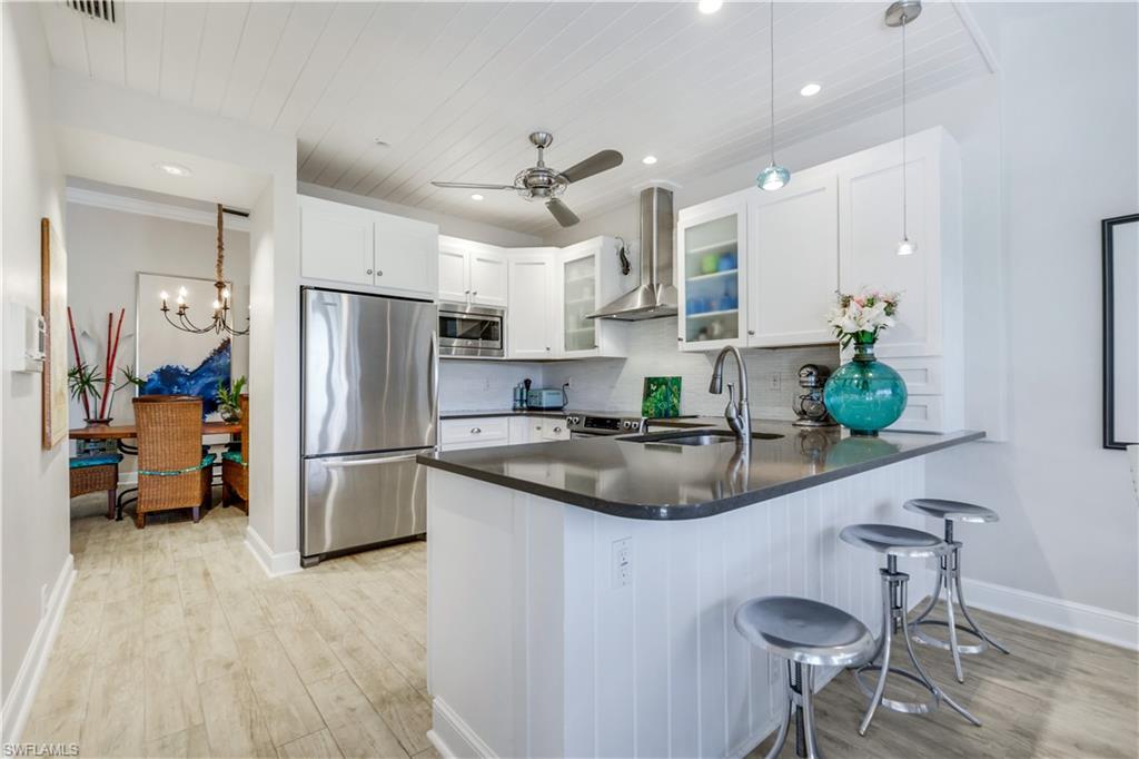 11831 Quail Village Way Naples, FL 34119 - Photo 12 of 32 a kitchen with stainless steel appliances a sink a refrigerator a counter and chairs
