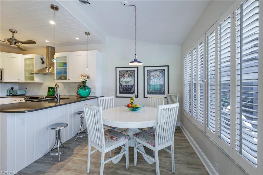 11831 Quail Village Way Naples, FL 34119 - Photo 13 of 32 a kitchen with stainless steel appliances a dining table chairs and white cabinets