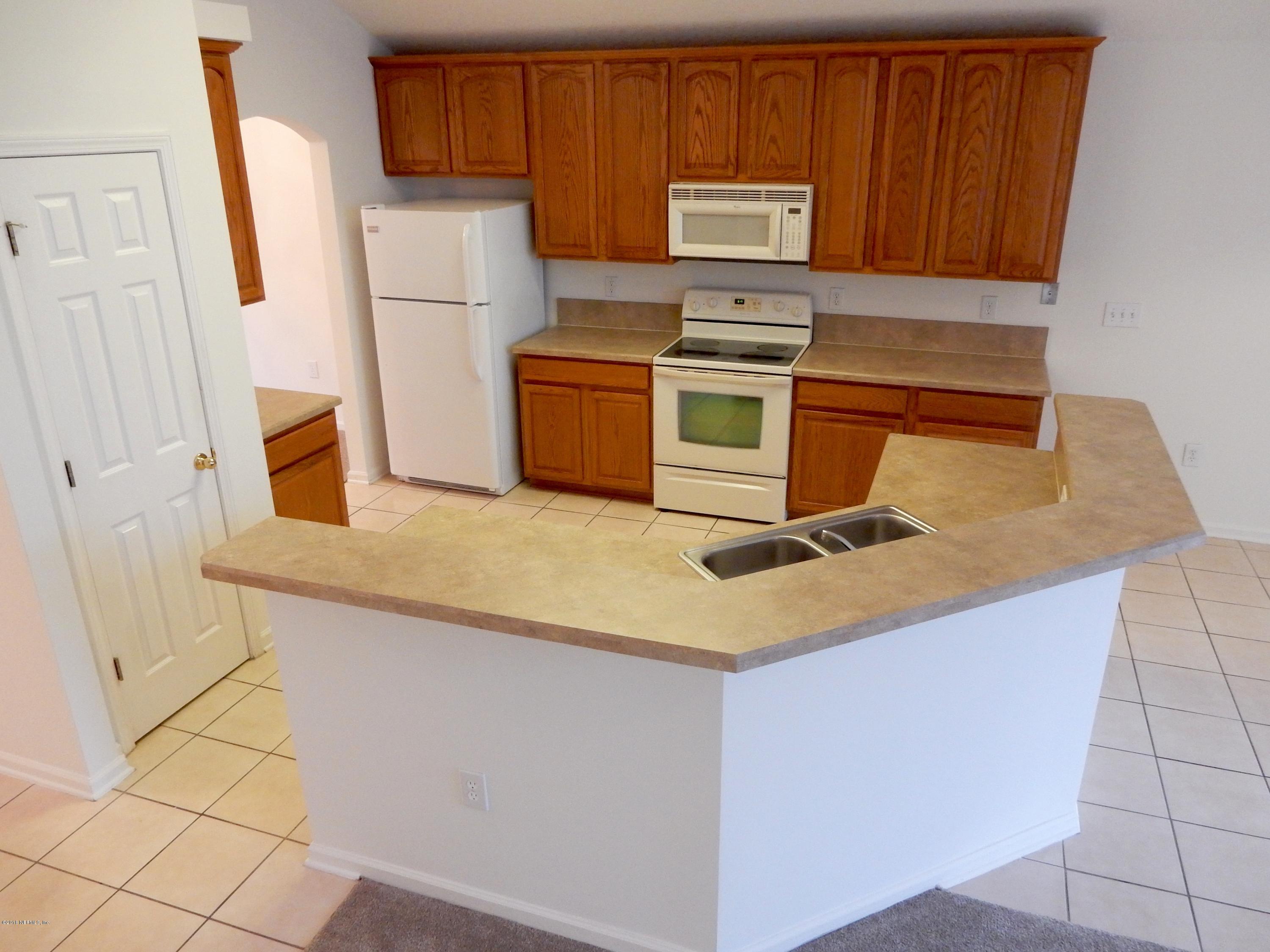 1528 Summerdown Way St. Johns, FL 32259 - Photo 7 of 28 a kitchen with wooden cabinets and white appliances