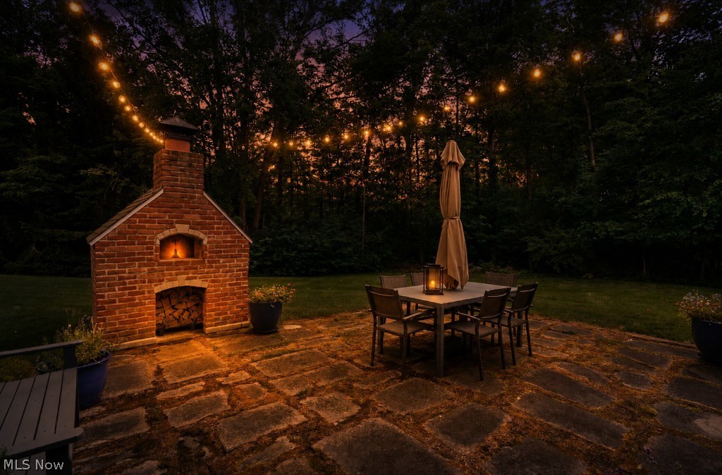 5046 Alger Road Richfield, OH 44286 - Photo 8 of 49 Expansive backyard featuring a brick oven structure with a wood storage alcove, a stone paver patio, and string lighting