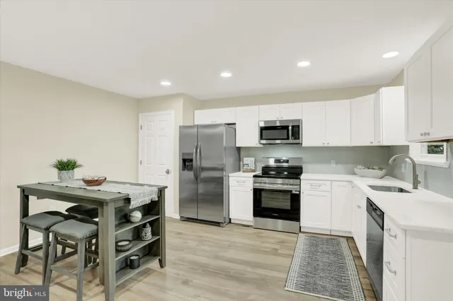 a kitchen with stainless steel appliances a stove a sink a microwave a refrigerator and cabinets