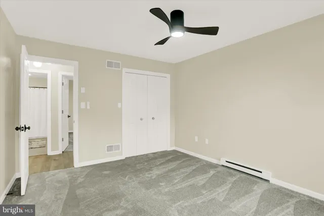 an empty room with a ceiling fan and window