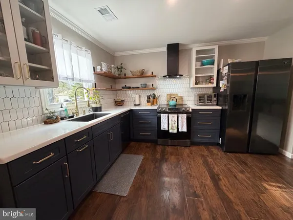 a kitchen with stainless steel appliances granite countertop wooden cabinets a refrigerator a sink a stove with wooden floors and cabinets