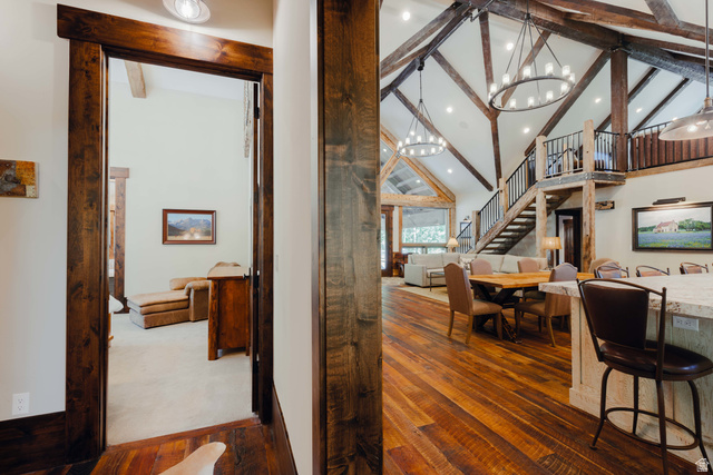 1667 West Tollgate Cyn Road Coalville, UT 84017 - Photo 33 of 61 Spacious living area featuring exposed wood beams, vaulted ceilings, wood-finish flooring, a contemporary chandelier, and a prominent staircase with metal railings