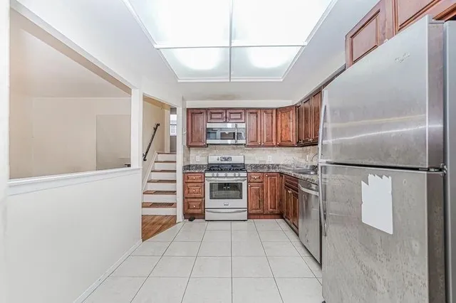 a kitchen with stainless steel appliances granite countertop a refrigerator and a stove top oven