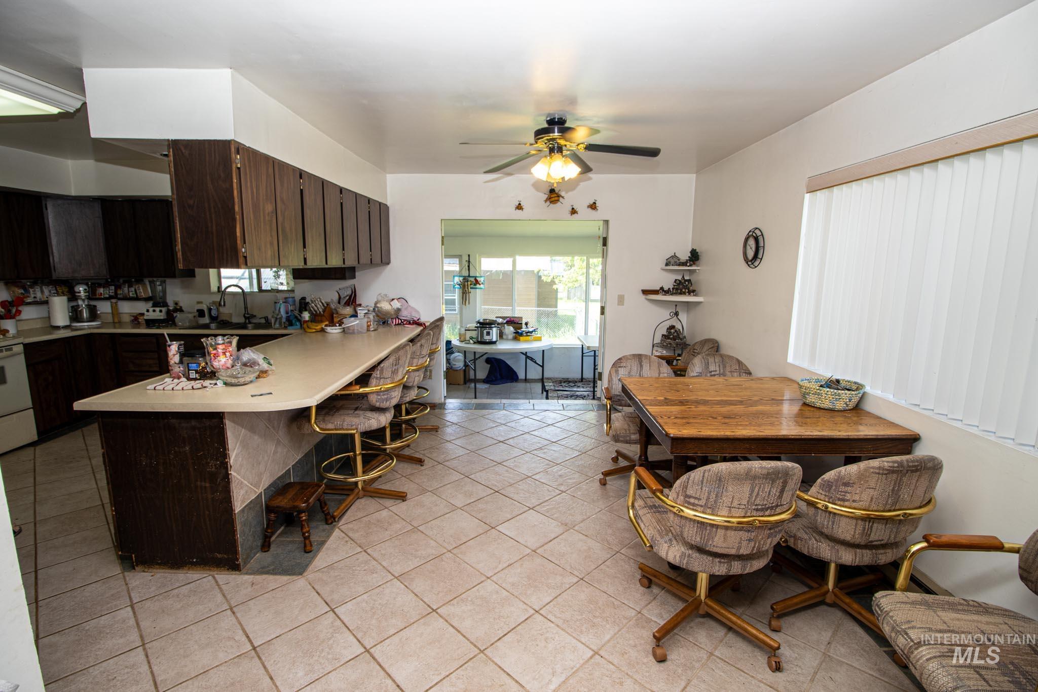 105 Weippe Avenue Weippe, ID 83553 - Photo 17 of 43 Kitchen featuring light countertops, light tile patterned floors, dark brown cabinets, a kitchen breakfast bar, and a peninsula