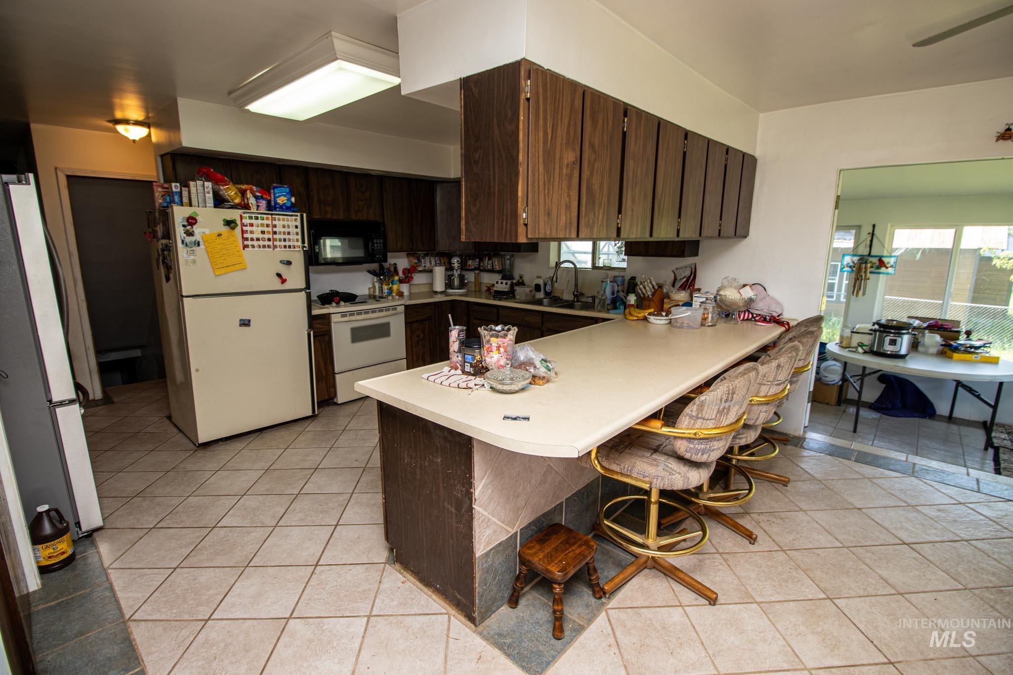 105 Weippe Avenue Weippe, ID 83553 - Photo 18 of 43 Kitchen with white appliances, a peninsula, light countertops, and light tile patterned floors