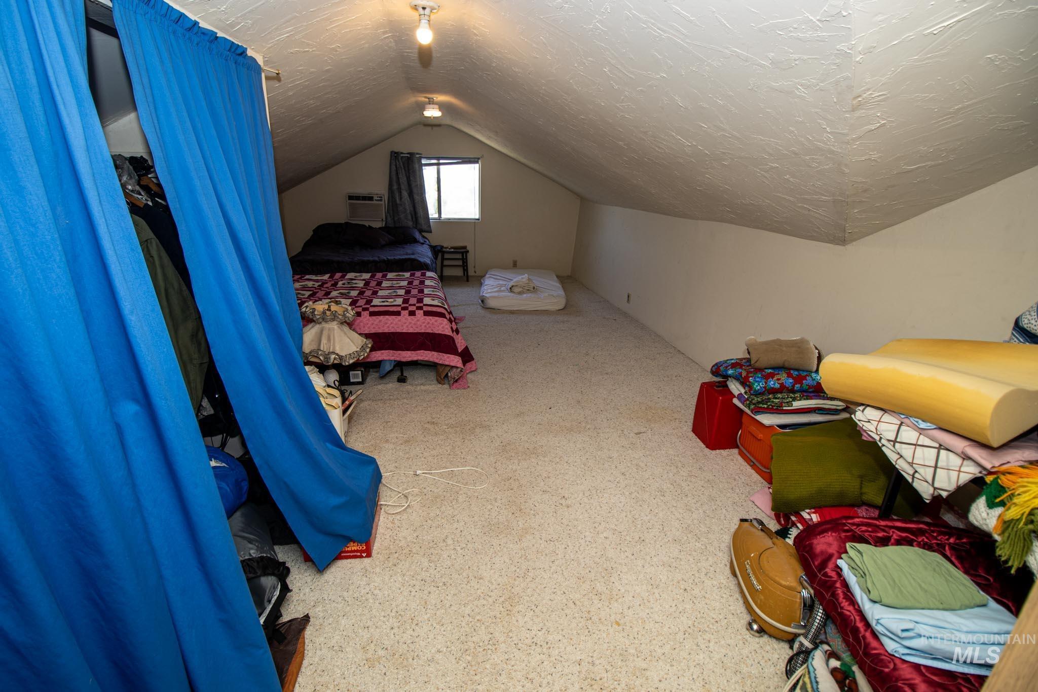 105 Weippe Avenue Weippe, ID 83553 - Photo 30 of 43 Bedroom featuring vaulted ceiling, a textured ceiling, a wall mounted AC, and carpet floors