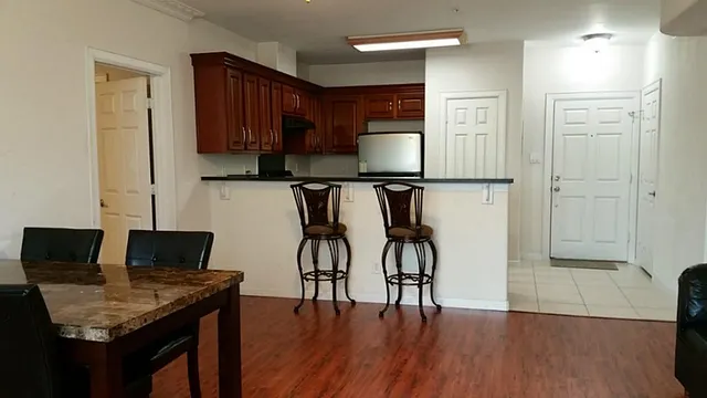 a kitchen with stainless steel appliances granite countertop a stove top oven a refrigerator a sink and dishwasher with wooden floor