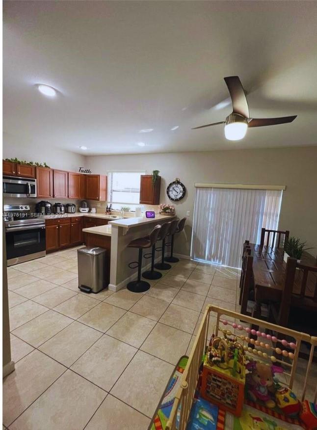 15076 Southwest 117th Terrace Miami, FL 33196 - Photo 10 of 31 a kitchen with stainless steel appliances granite countertop a stove top oven a sink a dining table and chairs with wooden floor
