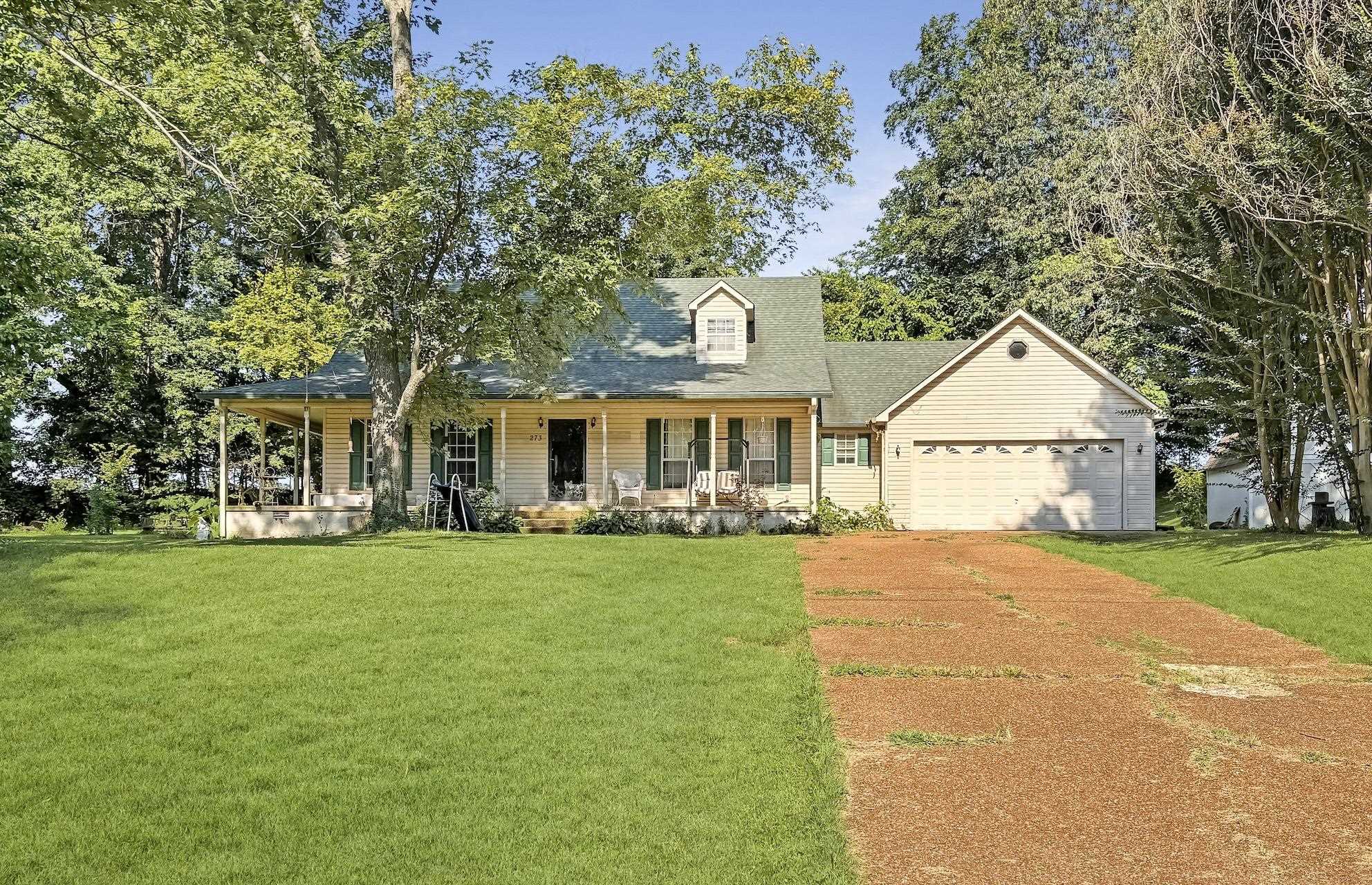 a front view of a house with a garden and trees