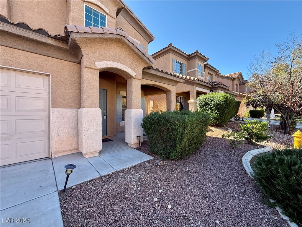 6031 Lamotte Avenue Las Vegas, NV 89141 - Photo 3 of 28 Entrance to property with stucco siding, a garage, a tiled roof, and a porch