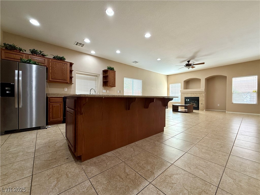 6031 Lamotte Avenue Las Vegas, NV 89141 - Photo 7 of 28 Kitchen featuring stainless steel refrigerator with ice dispenser, a breakfast bar, brown cabinets, recessed lighting, and open shelves