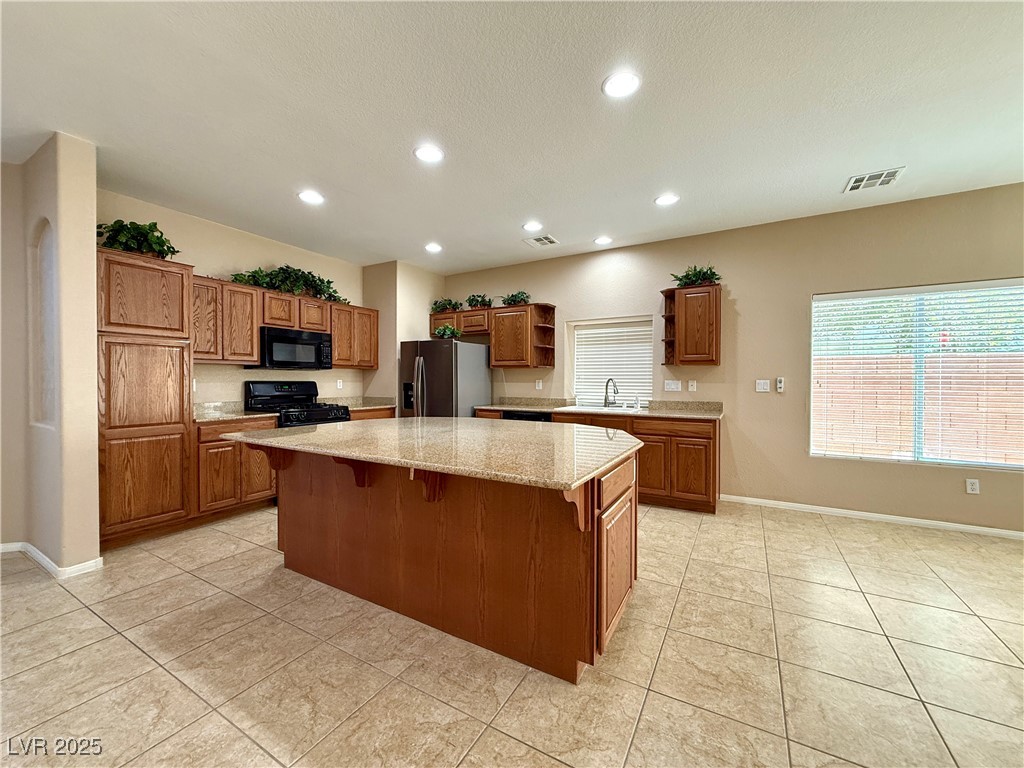 6031 Lamotte Avenue Las Vegas, NV 89141 - Photo 8 of 28 Kitchen with brown cabinetry, a center island, open shelves, recessed lighting, and a breakfast bar
