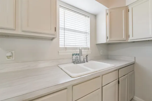a sink with white cabinets and a window
