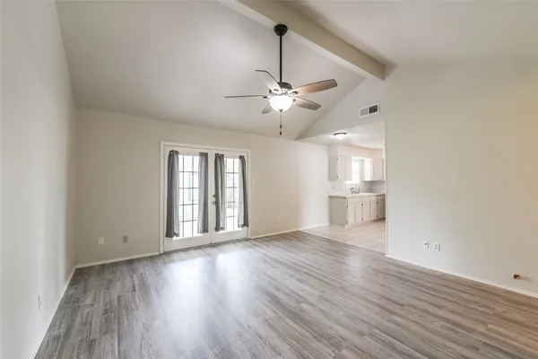 a view of an empty room with window and wooden floor