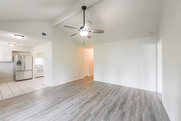 a view of empty room with wooden floor and ceiling fan