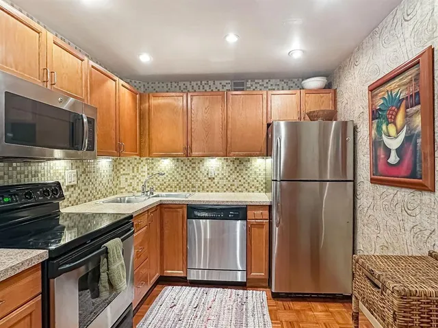 a view of a dining room and livingroom with furniture wooden floor a rug a painting and a chandelier