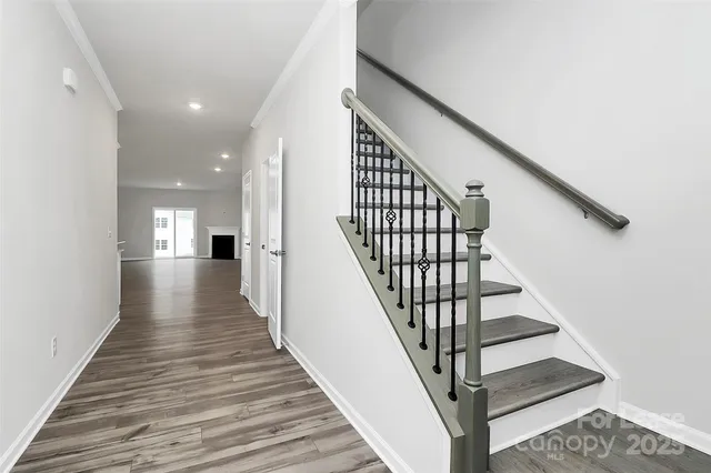 a view of staircase with wooden floor and white walls