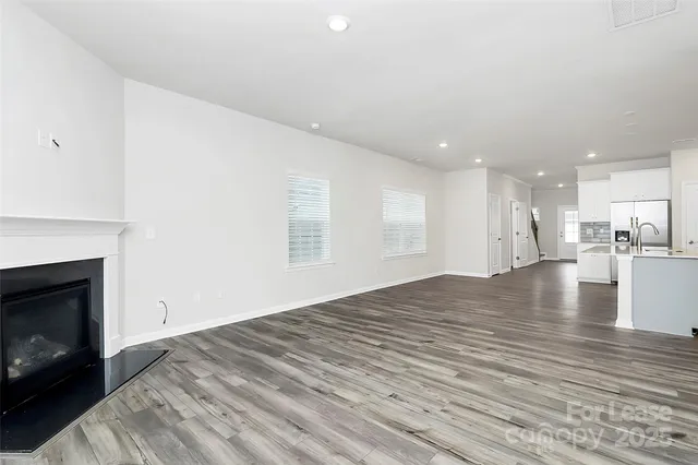 a view of empty room with kitchen and fireplace