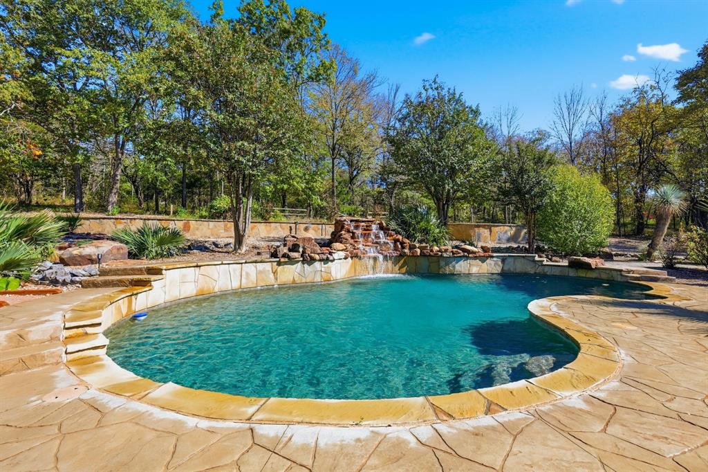 Rock Waterfall Spilling into a Resort Style Diving Pool Surrounded By Mature Trees and Natural Stone Decking. Your Own Private Margaritaville! Stamped Cement Decking and Flagstone Decking.