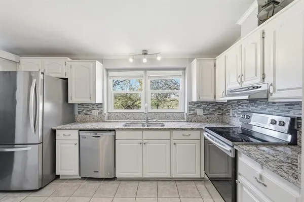 a kitchen with granite countertop white cabinets white appliances and sink
